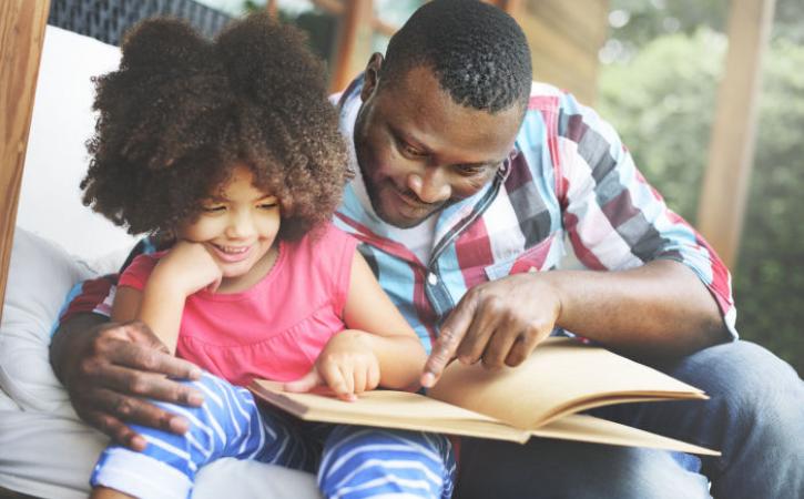 African American father and daughter reading book together